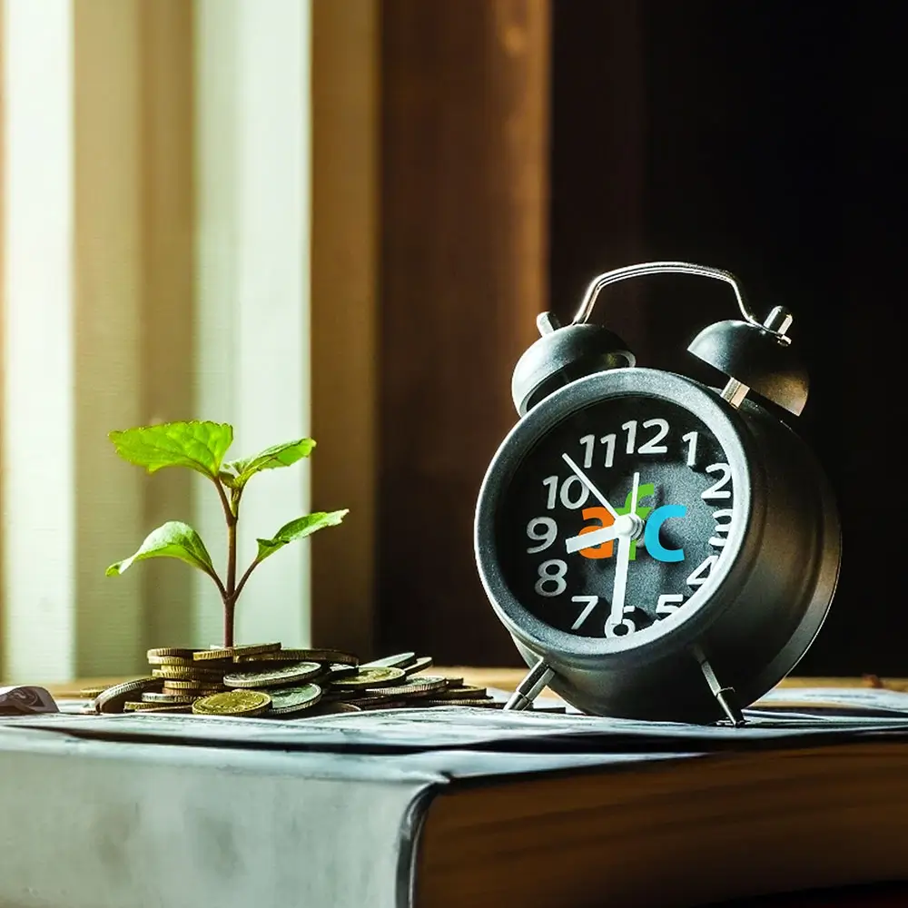 An alarm clock and few coins on a table with a small plant, symbolising growth and finance management